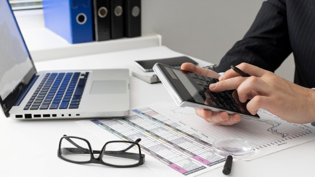 "Businessman calculating financial data with a calculator and documents, representing VAT and tax consultancy services in Dubai."